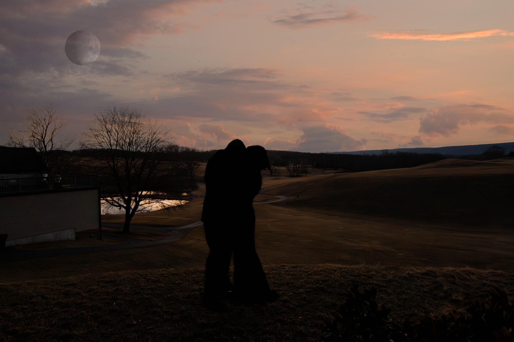 Artistic silhouette of a couple beneath a moonlit sunset sky
